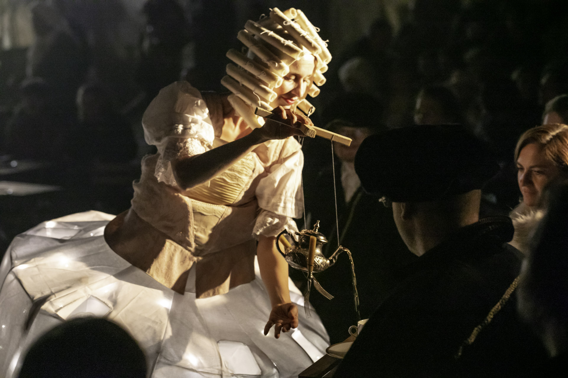 Aktorka ubrana w barokowy strój, nalewa herbaty z imbryczka