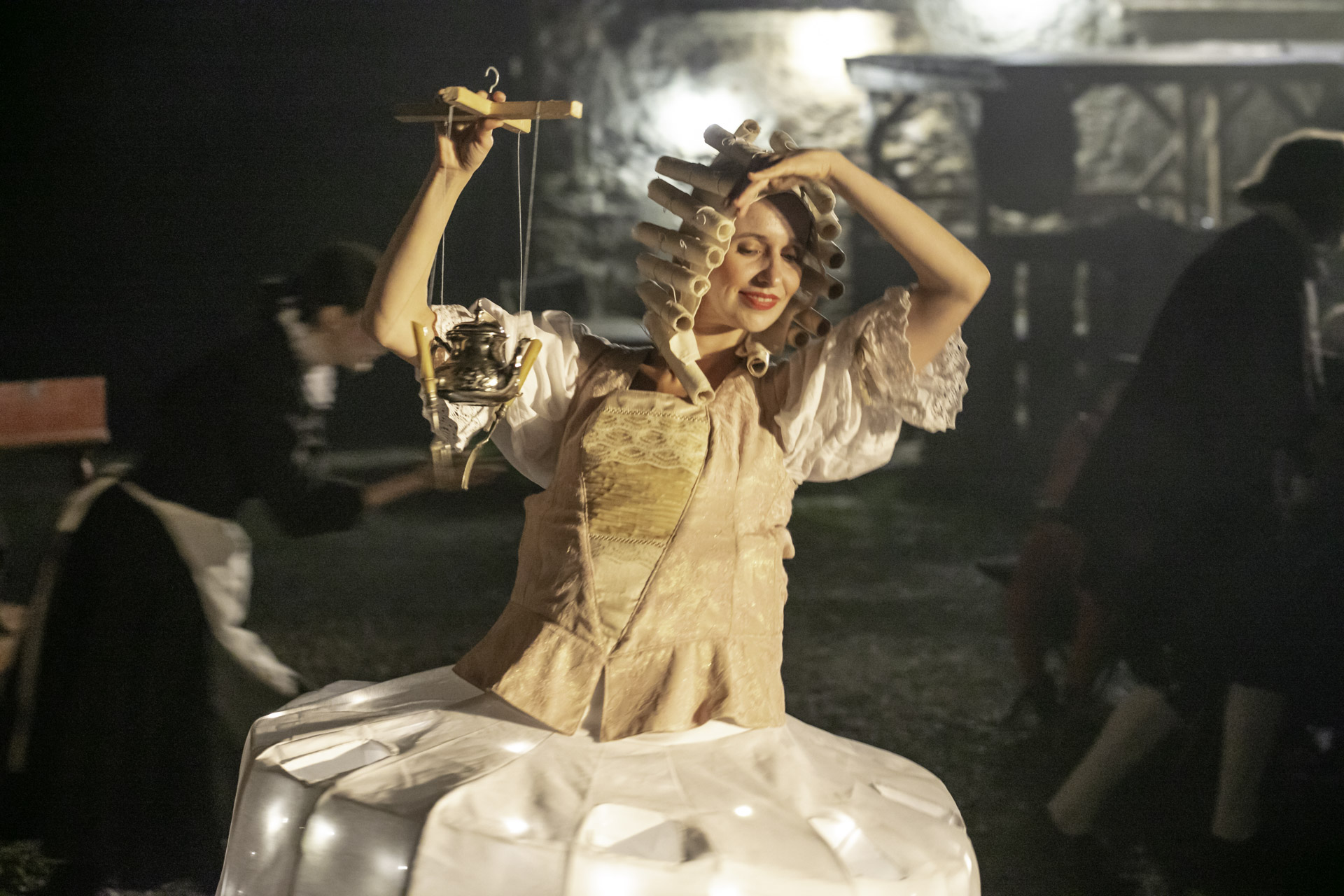 Aktorka ubrana w barokowy strój, trzyma w ręku imbryczek do herbaty